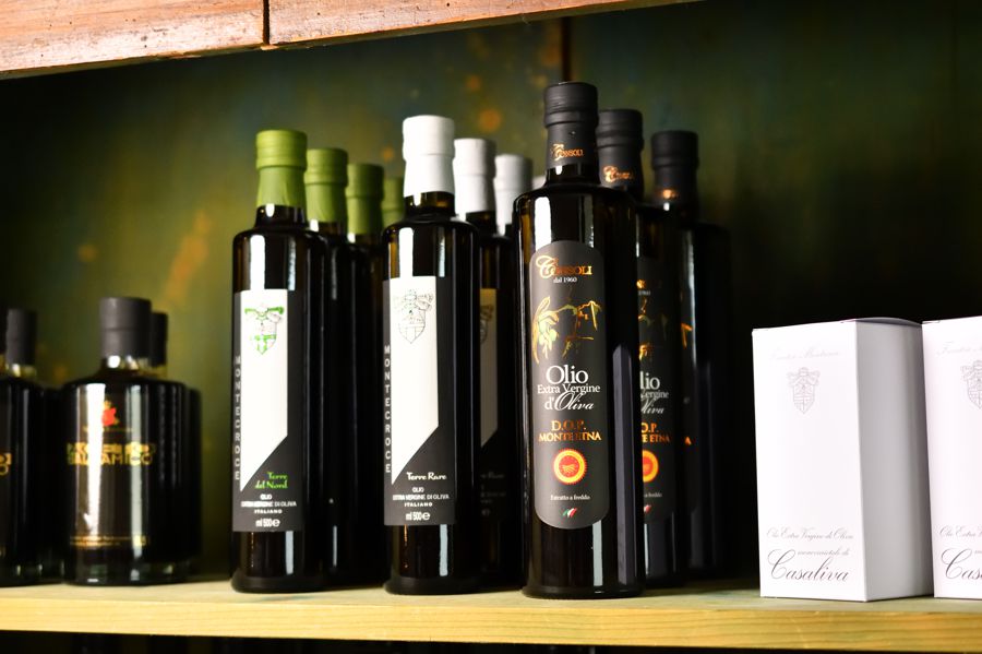 Ausstellung verschiedener Ölflaschen im Regal.