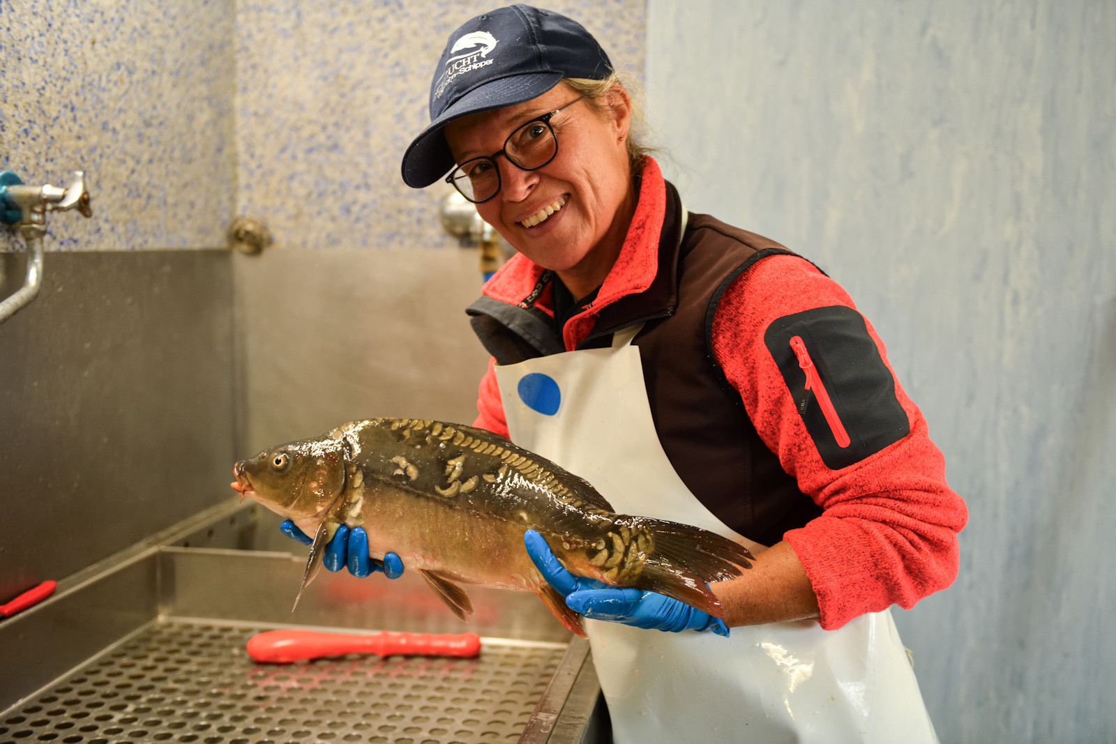 Isabelle Vollmann-Schipper mit einem Fisch in der Hand lächelt in die Kamera.