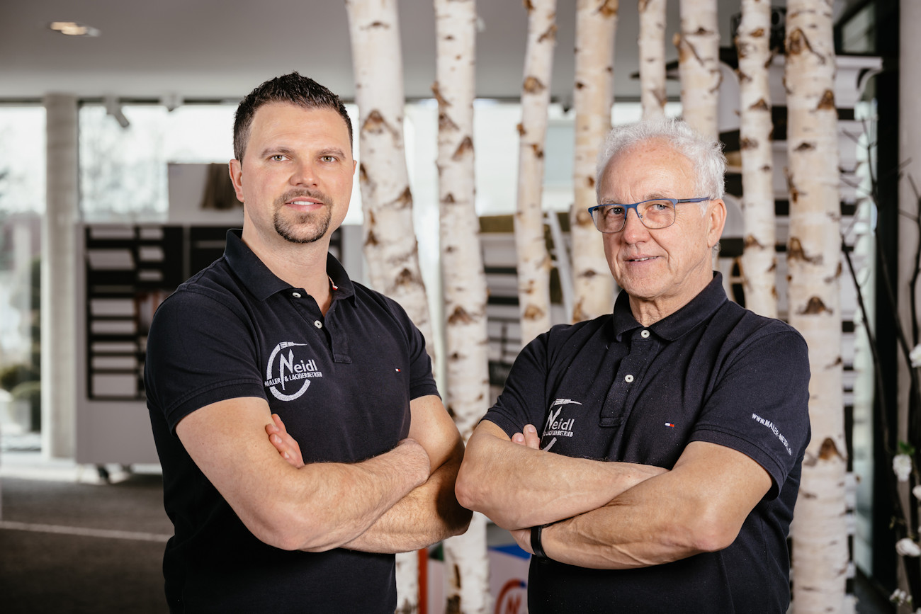 Christian Neidl und sein Vater stehen vor Birkenstämmen im Ausstellungsraum.