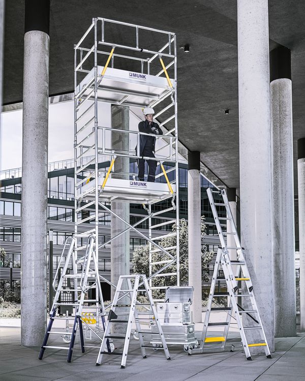 Zwei Feuerwehrleute steigen über ein MUNK-System auf ein brennendes Gebäude, im Hintergrund ein Helikopter im Einsatz.