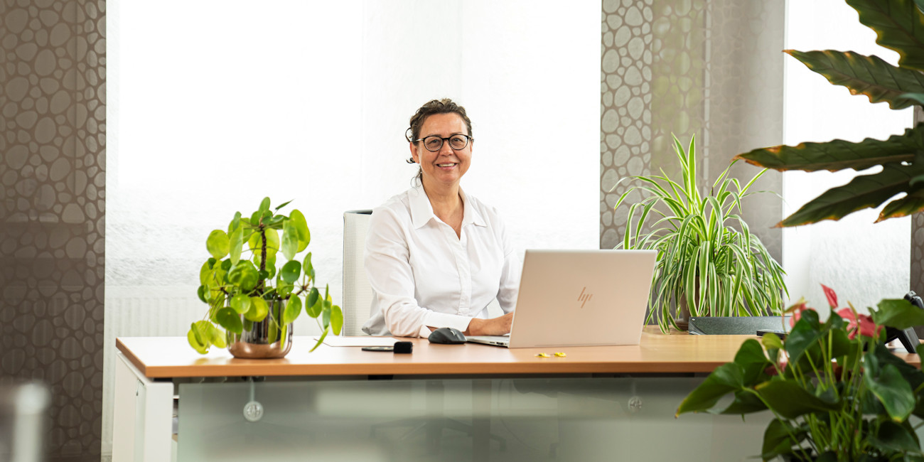 Miriam Albrecht sitzt am Schreibtisch und arbeitet am Laptop.