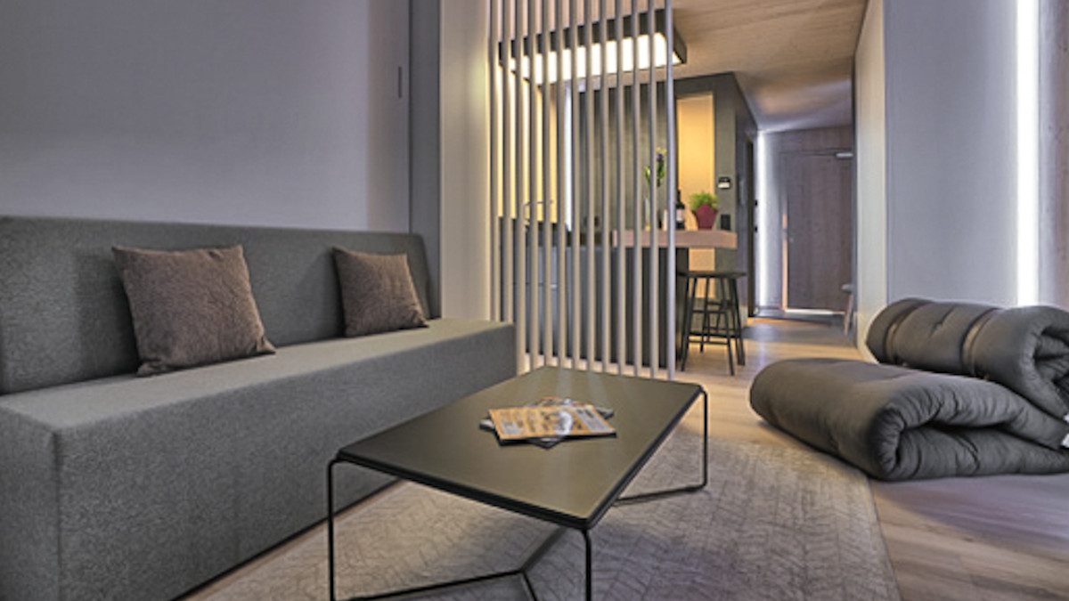Musterbild von Zugspitz – Serviced Apartments in Augsburg einer Wohnung von innen mit Sofa und Tisch, im Hintergrund die Küche.